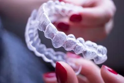 woman holding her Invisalign aligners 