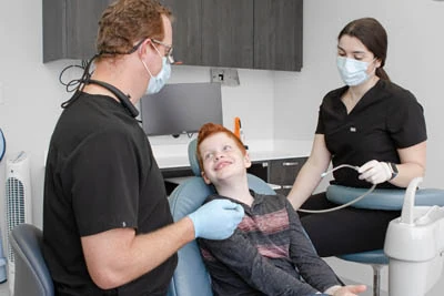 young patient looking up at doctor and staff member in dental chair