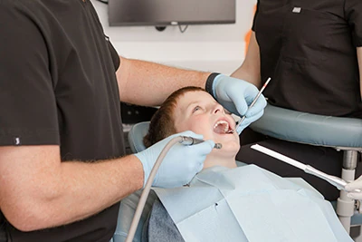 child getting their teeth worked on in dental chair